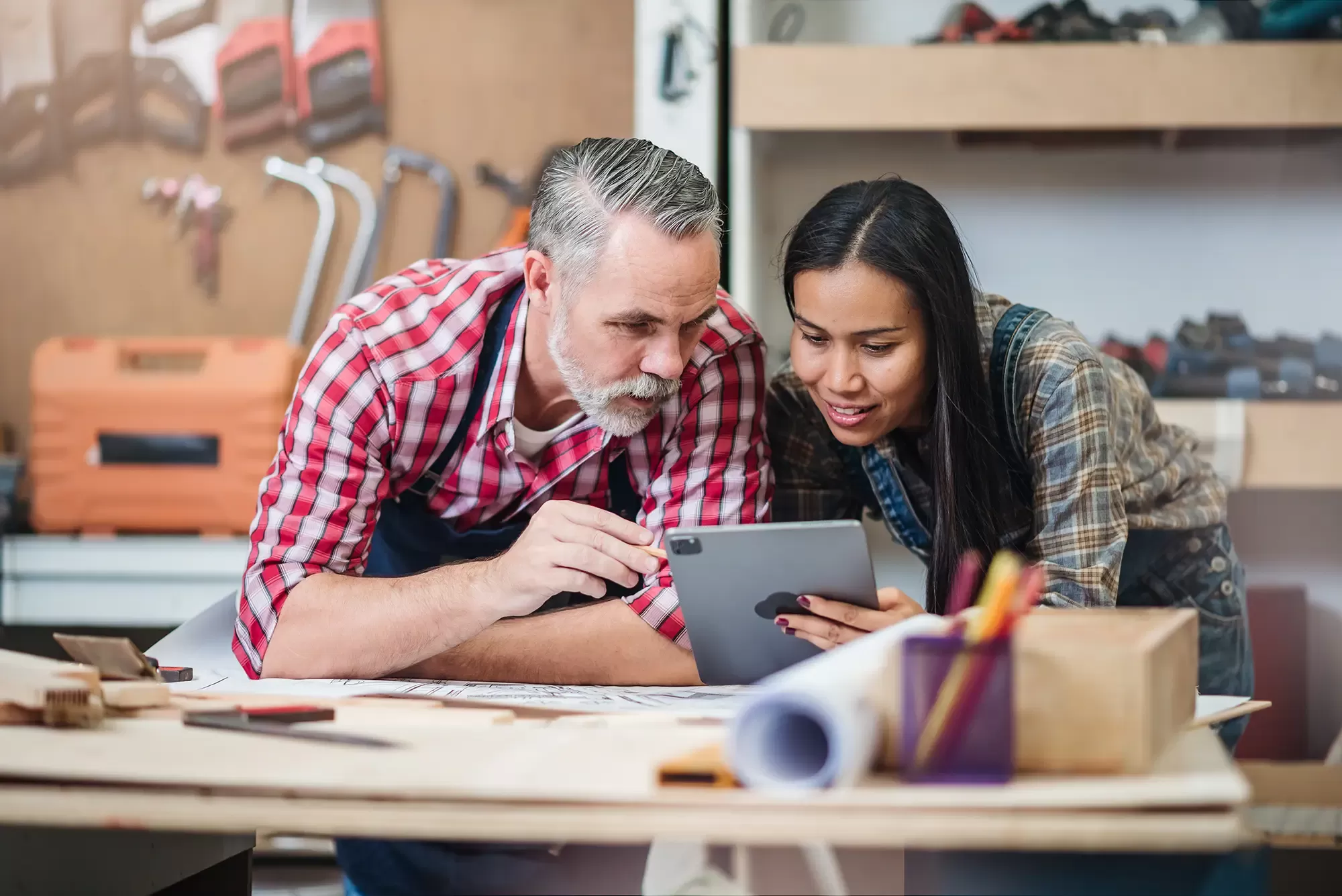 Adobe Stock 562160446 Small business furniture owner and professional architect interior designer working in carpenter workshop with blueprint and tablet discussing about home furnishing design project copy
