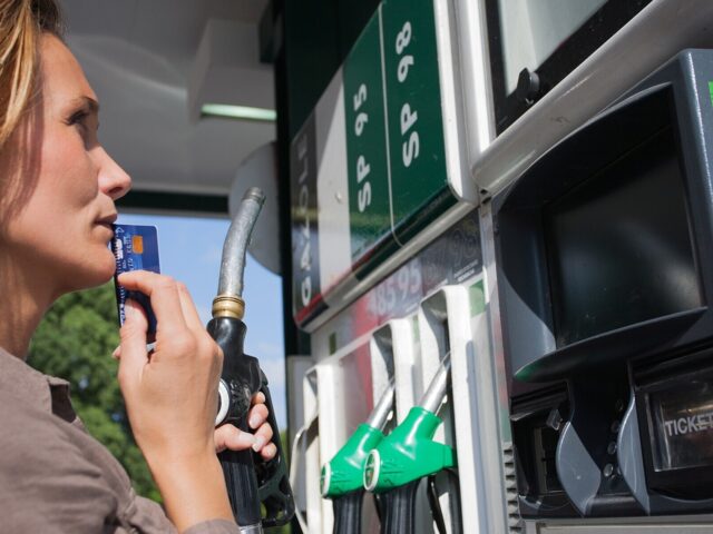 Woman with credit card in hand hesitates at gas pump 978b8d064138018a1dfad71b9882dd21