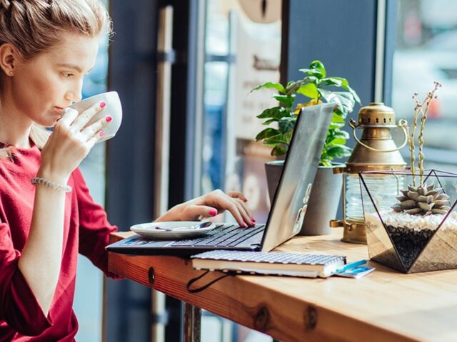 Young woman sips coffee and views laptop in cafe 978b8d064138018a1dfad71b9882dd21