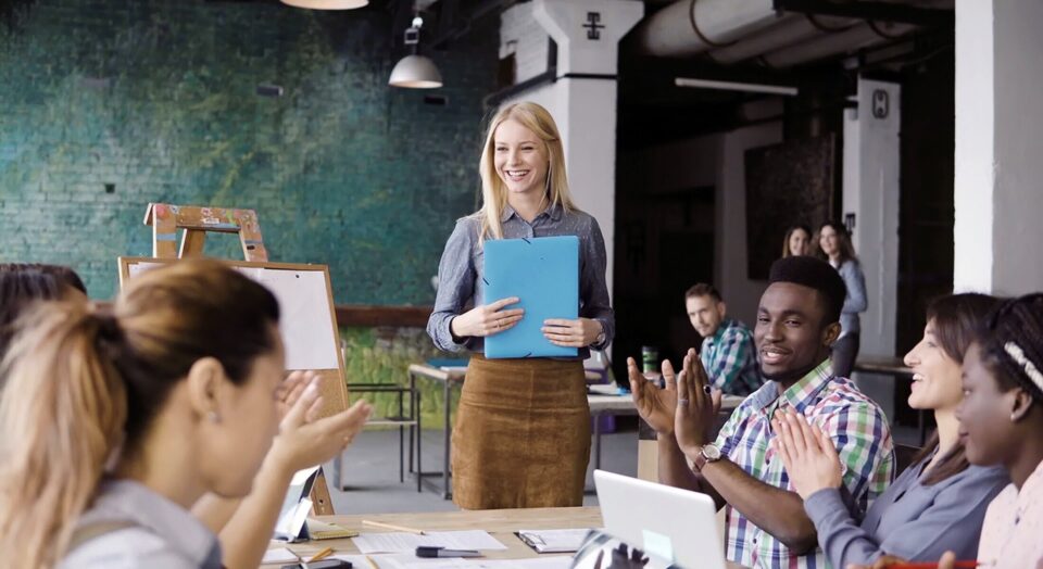 Professional woman gives presentation to applauding team members 978b8d064138018a1dfad71b9882dd21