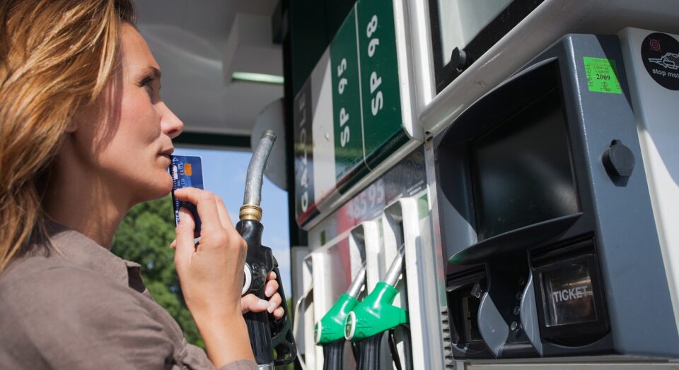 Woman with credit card in hand hesitates at gas pump 978b8d064138018a1dfad71b9882dd21