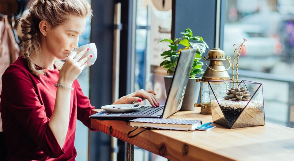 Young woman sips coffee and views laptop in cafe 978b8d064138018a1dfad71b9882dd21